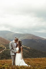 Wall Mural - gorgeous bride and stylish groom posing hugging,  boho wedding couple, luxury ceremony at mountains with amazing view
