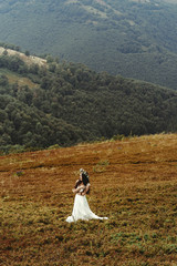 Wall Mural - gorgeous bride posing on background of  sunny landscape,  boho wedding, luxury ceremony at mountains
