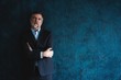 © opolja - Serious mature man posing in front of a dark blue background with copy space.