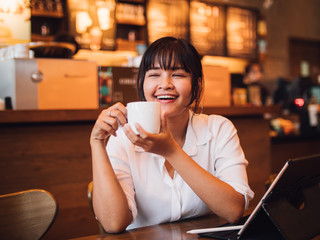 Asian woman drinking coffee in cafe and using laptop computer for working business online marketing