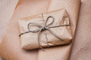 Wall Mural - Brown craft package with bow from hemp tie. Wrapped parcel on paper background.