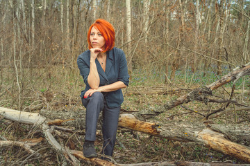 Young woman with red hair among trees