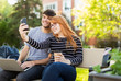 © Designpics - A young man and young woman sit together on a bench on the university campus taking a self-portrait on a smart phone while drinking coffee; Edmonton, Alberta, Canada