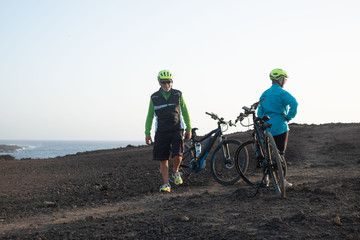 Relaxing moment after the bike tour excursion. Healthy lifestyle of two senior people. Sea on the background