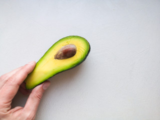 Avocado in hand, on white background. Man Proposing To Woman With Engagement Ring In Avocado. Closeup. Cut avocado