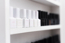 Different Gel Polishes In Jars And Bottles For Nails Are In The Window Of The Manicurist. Nail Polishes For Manicure And Pedicure Are On The Shelf