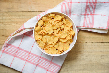 Cornflakes breakfast in bowl on kitchen cloth wooden background for cereal healthy food