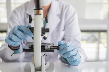 Wall Mural - a scientist hands working in laboratory with test tube microscope and solutions.