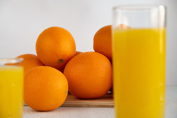 Wall Mural - A glass of orange juice is on the table next to oranges.