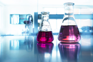 two glass flask with pink solution in chemistry science blue laboratory background