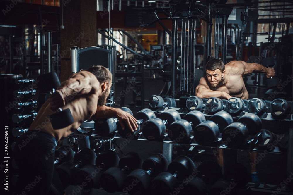 Good looking young man bodybuilder doing triceps kickback lifting ...