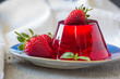 Photo of fruit jelly with fresh strawberry. Healthy food. Strawberry jelly on white plate. Summer dessert with fruit jelly and fresh strawberry.
