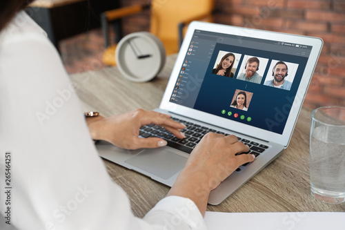 Fotomural Woman having video chat with colleagues at table in office, closeup