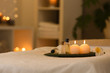 © New Africa - Cosmetics and burning candles on massage table in spa salon, space for text