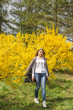 © svitlini - A girl walks past bright yellow bushes. Spring happy lifestyle
