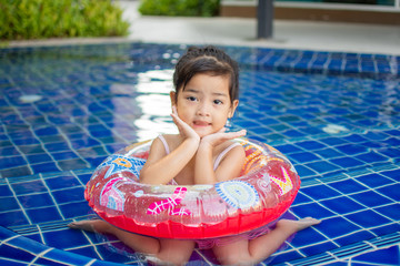 cute little girl feel happy play and swimming at swimming pool , sunny day and soft focus.