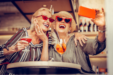 Laughing happy old women wearing red weird sunglasses