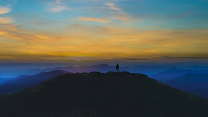 Wall Mural - The man silhouette on a mountain against the beautiful sunset
