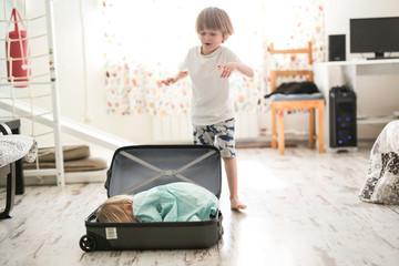 Wall Mural - Children play in a suitcase, travel concept. Blond