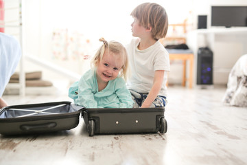 Wall Mural - Children play in a suitcase, travel concept. Blond