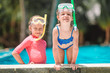 © travnikovstudio - Adorable little girls playing in outdoor swimming pool