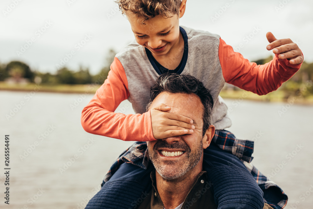 Father and son playing near the lake - obrazy, fototapety, plakaty 
