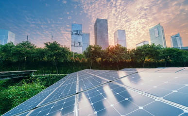 Ecological energy renewable solar panel plant with urban landscape landmarks in sunset