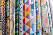 Close-up rows of pieces of fabric made of cotton, polyester, tapestry and other materials of different colors and prints for sewing curtains, bedding and clothing
