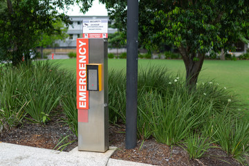 An emergency button telephone intercom system on the side of a public path.