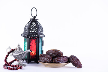 Ramadan food and drinks concept. Ramadan Lantern with arabian lamp, wood rosary, dates fruit and lighting on white background.