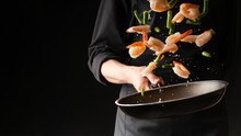 Seafood, Professional Cook Prepares Shrimps With Sprigg Beans. Cooking Seafood, Healthy Vegetarian Food And Food On A Dark Background. Horizontal View. Eastern Kitchen