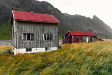Old Damaged Wooden House And Barn With A Red Corrugated Iron Rooftop In The Village Vinstad On Lofoten Islands In Norway.