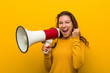 © Asier - Young european woman holding a megaphone cheering carefree and excited. Victory concept.