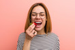 © Asier - Portrait of young woman tasting a fresh strawberry
