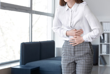 Sticker - Young woman suffering from abdominal pain in office