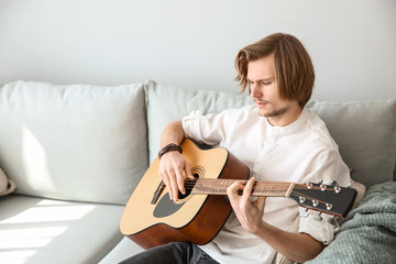 Canvas Print - Handsome young man playing guitar at home