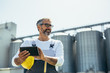 © cherryandbees - worker using tablet in front of grain silo