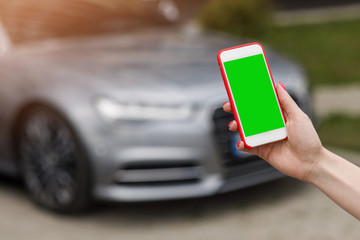 Mockup image of woman holding mobile phone with blank screen. Business woman using phone on car background.