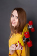 © Kiryl Lis - Portrait of positive young attractive girl wearing yellow blouse holding yellow skateboard.
