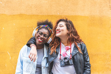 Two Teenage Latin Girls Standing Together Over A Yellow Wall.