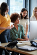 © Monkey Business - Four female creatives working around a computer monitor in an office, side view, vertical, close up