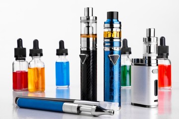 Wall Mural - Electronic cigarettes and bottles with vape liquid on white background