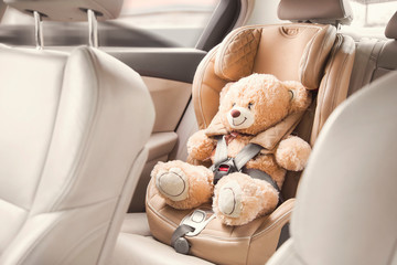 baby child seat car. a beige teddy bear is fastened with seat belts in a car seat. travel by car