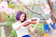 A young woman plays the violin in the yard. Musician. 
