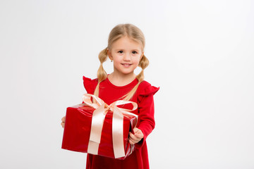 Wall Mural - Portrait of little girl in red dress on isolated white background. Smiling Girl in shirt with gifts in hands looking at camera. Isolated gray background. The concept of celebrating, giving and receivi