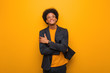 © Asier - Young business african american man over an orange wall smiling confident and crossing arms, looking up