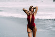 © romannoru - Sexy model with big breasts in a red swimsuit sunbathes on black sand beach.