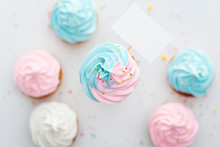 Top View Of Delicious Pink, White And Blue Cupcakes With Sprinkles And Blank Card Isolated On White