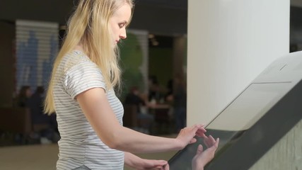 Woman using interactive touchscreen display at mall - scrolling and touching.
