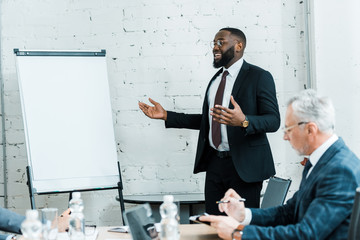 Wall Mural - happy african american business coach talking near white board and colleague